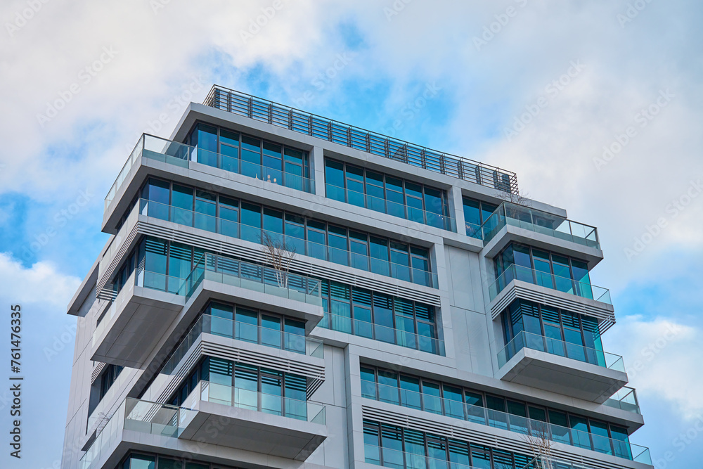 Towering contemporary building in city against cloudy sky, Modern architecture exterior with balconies and glass windows. Towering contemporary building in city against cloudy sky, Modern architecture exterior with balconies and glass windows.
