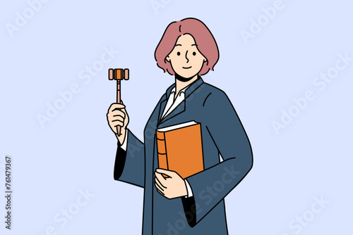 Woman judge with wooden claw and constitution in hands is ready to announce fair legal decision. Girl in judge robe smiles, rejoicing in building successful career in field of law.