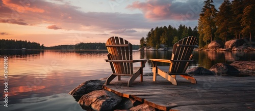 Two wooden chairs on a wooden pier overlooking a lake at sunset in Finland photo