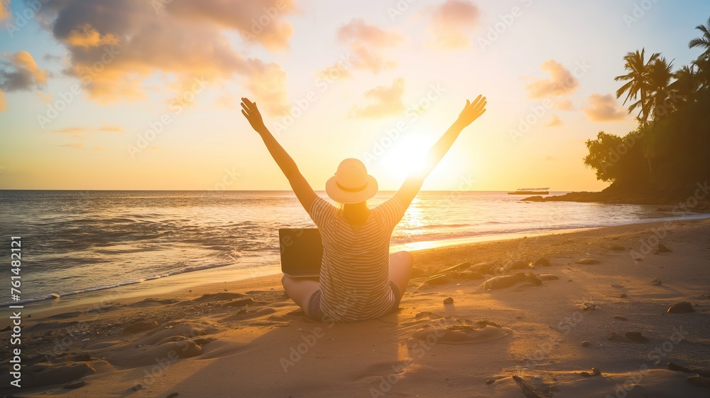 A woman sitting on the beach with a laptop, her arms raised in joy and celebration of success. A beautiful sunset at a tropical island in the background. A concept for a freedom lifestyle 