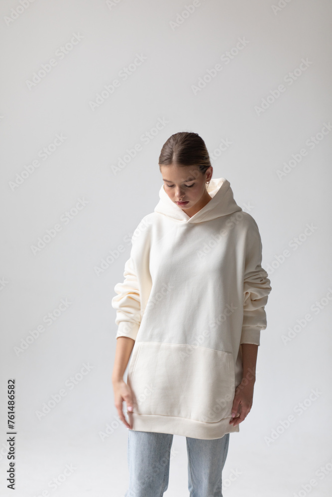 Beautiful blonde woman in a white hoodie and blue jeans posing on a white background Beautiful blonde woman in a white hoodie and blue jeans posing on a white background