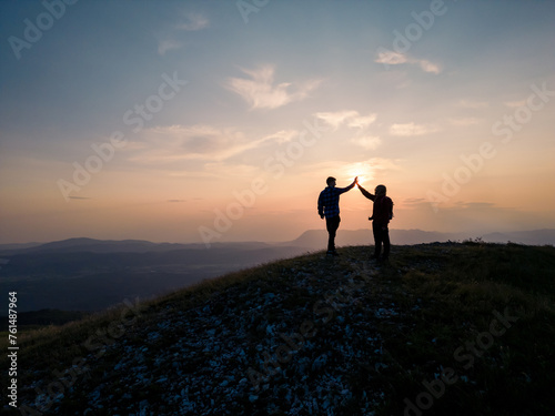 Teenage hiking adventure  a cheerful teen girl and a teen boy giving high five on the mountain top  enjoying success. Fun  inspiration  and recreation concepts.