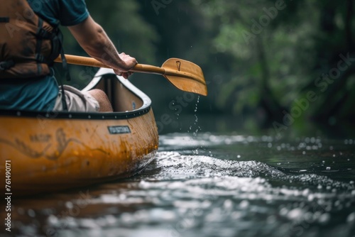 A man paddling a canoe down a river. Suitable for outdoor activities concept