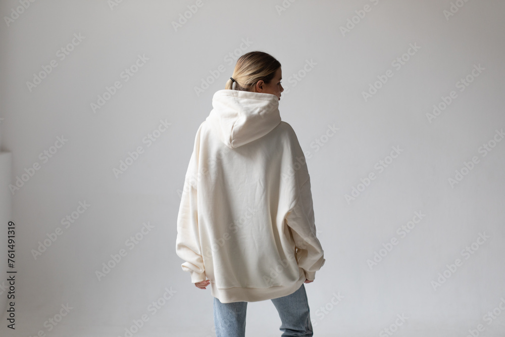 Beautiful blonde woman in a white hoodie and blue jeans posing on a white background Beautiful blonde woman in a white hoodie and blue jeans posing on a white background