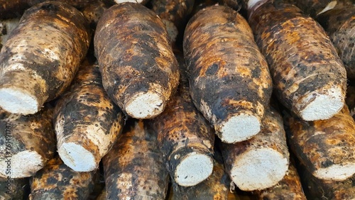Close up pile of tasty fresh raw organic brown taro root ready to cook sold at the market as a background.