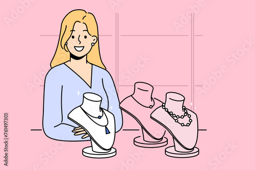 Woman stands in jewelry store near display case with necklaces made of diamonds and precious stones or pearls. Girl visitor to jewelry boutique purchases new expensive piece of bijouterie.