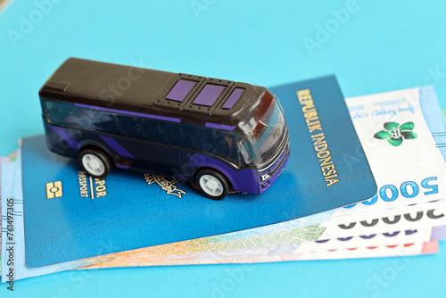 Blue Republic Indonesia passport with money and toy bus on blue background close up. Tourism and travel concept photo