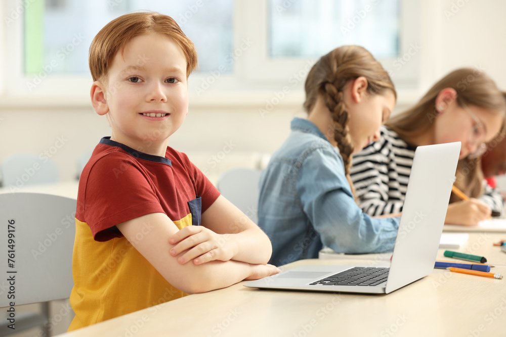 Smiling boy with his classmates studying in classroom at school Smiling boy with his classmates studying in classroom at school