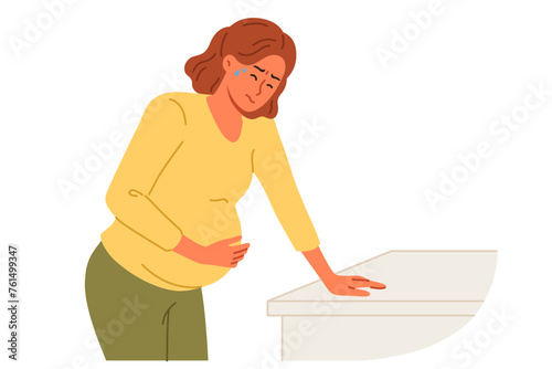 Obraz na płótnie Pregnant woman holds stomach, standing near cabinet, experiencing pain due to complications caused by fetal development disorders. Pregnant girl needs hospitalization to avoid miscarriage w salonie