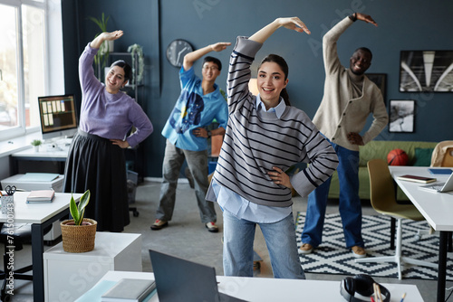 Bilde på lerret Diverse group of cheerful people enjoying stretching exercises in morning starti
