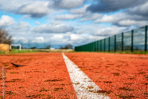 Red running track with white lines and blue sky in the background.