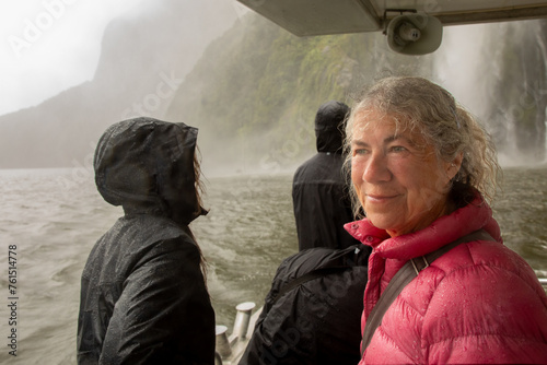 A bedraggled visitor admires the spectacular Milford Sound, one of the wettest places on the planet, from aboard a tour boat. photo
