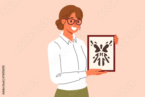Rorschach test in hands of woman psychotherapist, want to find out psychological state patient with mental disorder. Girl psychotherapist with smile demonstrates abstract painting in form of blot.