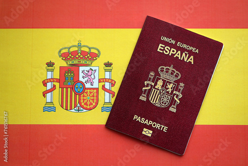 Red Spanish passport of European Union on national flag background close up. Tourism and citizenship concept