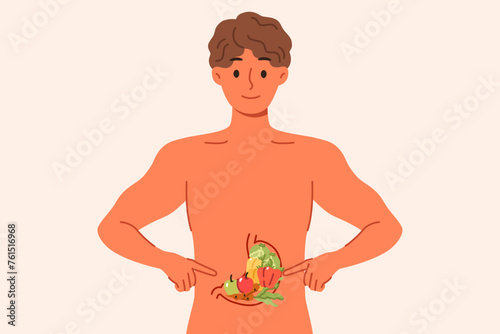 Man recommends healthy diet, points to vegetables inside stomach, stands with naked torso. Diet guy explains benefits of eating fresh produce from farmer market or organic section of supermarket