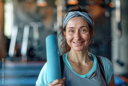 A woman holding a yoga mat in a gym, perfect for fitness and wellness concepts