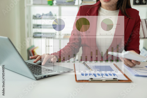 Attractive Asian accountant in suit calculating cash bill of audit and balance sheet working on quarterly report using laptop thinking about project plan. Analyze marketing or financial data online