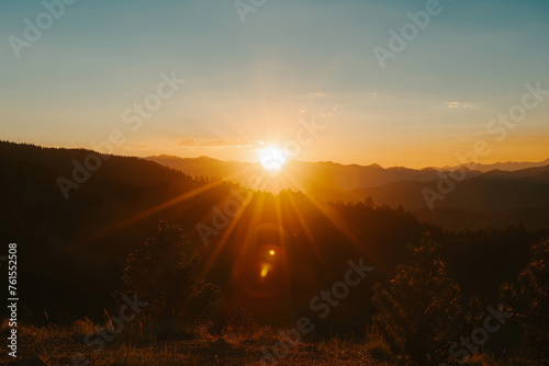 Sunset in mountains. Sun dips behind mountain peaks with golden light. Beautiful nature landscape