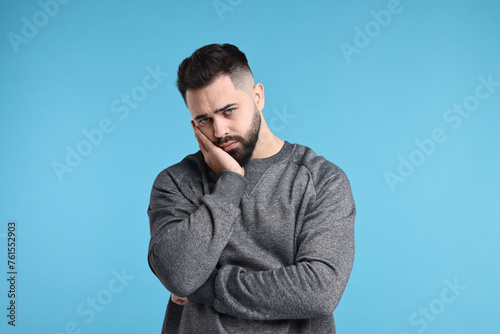 Portrait of sad man on light blue background