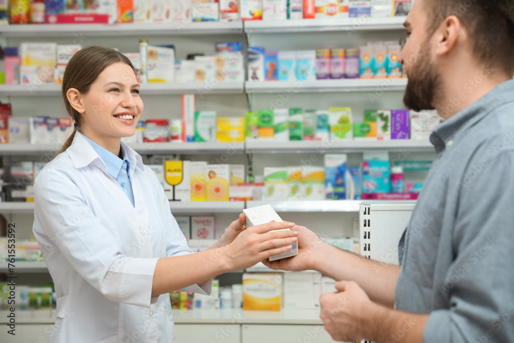 Professional pharmacist giving medicine to customer in modern drugstore