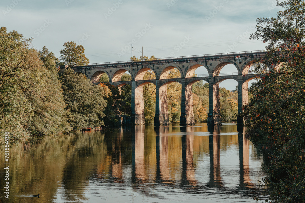 Fototapeta premium Railway Bridge with river in Bietigheim-Bissingen, Germany. Autumn. Railway viaduct over the Enz River, built in 1853 by Karl von Etzel on a sunny summer day. Bietigheim-Bissingen, Germany. Old