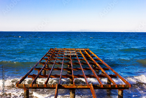 A rusty and old pier on the blue sea. Pier and sea view.