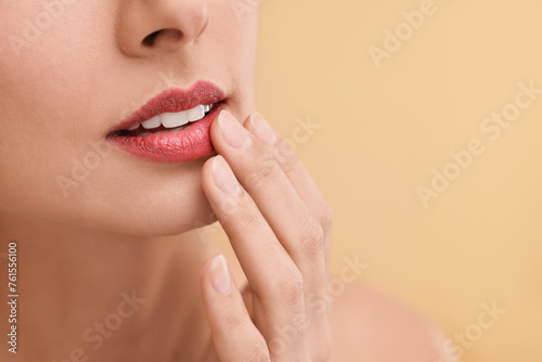 Woman with beautiful lips on beige background  closeup. Space for text