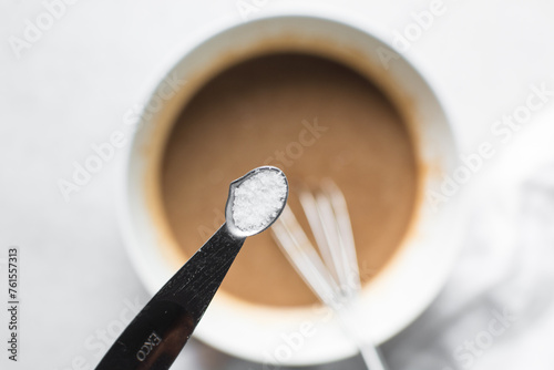 Overhead view of baking soda or baking powder in a silver measuring spoon, A teaspoon of baking soda or baking powder photo