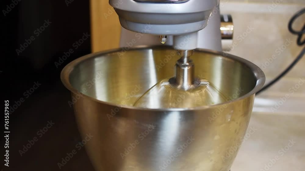 Side view of a working stainless bowl kitchen mixer. Side view of a working stainless bowl kitchen mixer.