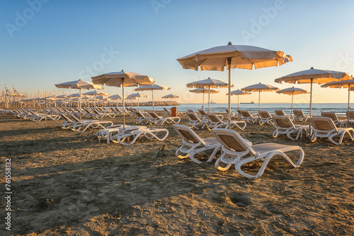 View of the Larnaca sandy beach at sunrise, tourist resort, Cyprus. Scenic seascape with beach umbrellas and sun loungers, travel background, summer holidays concept