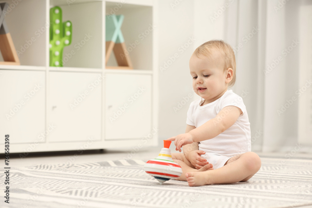 Children toys. Cute little boy playing with spinning top on rug at home, space for text Children toys. Cute little boy playing with spinning top on rug at home, space for text