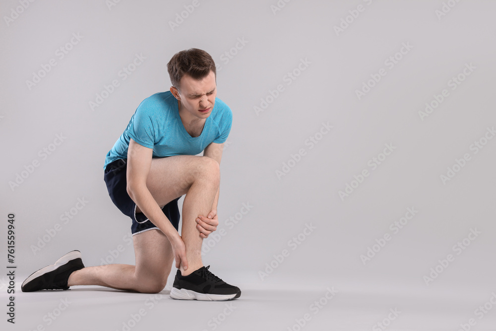 Man suffering from leg pain on grey background. Space for text Man suffering from leg pain on grey background. Space for text