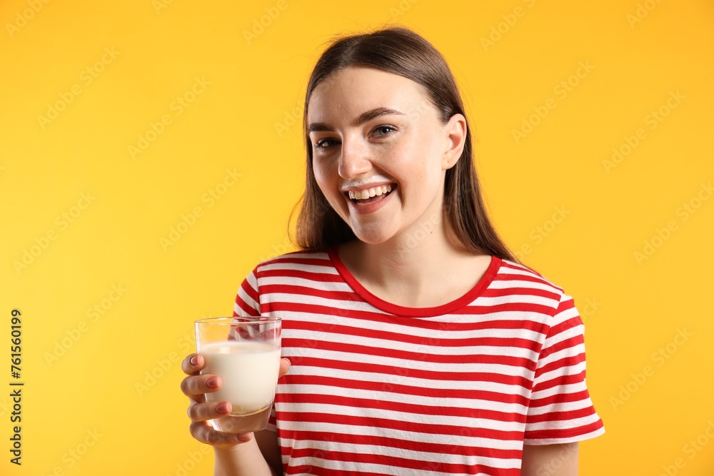 Happy woman with milk mustache holding glass of tasty dairy drink on orange background Happy woman with milk mustache holding glass of tasty dairy drink on orange background
