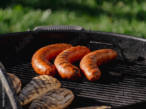 Sausage links and chicken cooking outside on a bbq grill  © Cam