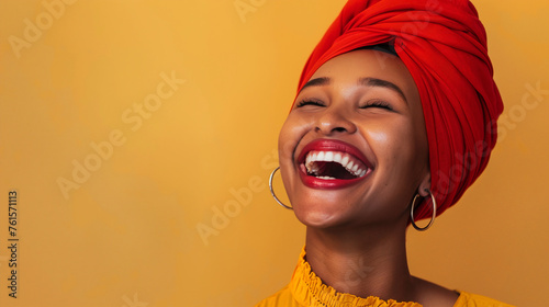 An exuberant woman in a vibrant red headscarf and yellow blouse laughs wholeheartedly against a warm yellow backdrop, conveying an infectious joy and vivacious spirit. photo