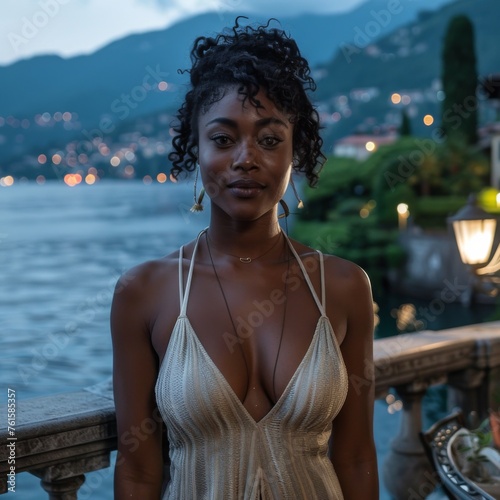 In the style of Instagram influencer, A gorgeous black woman wearing a neutral colored sundress poses for the camera on a balcony with Lake Como Italy as her backdrop, at night 