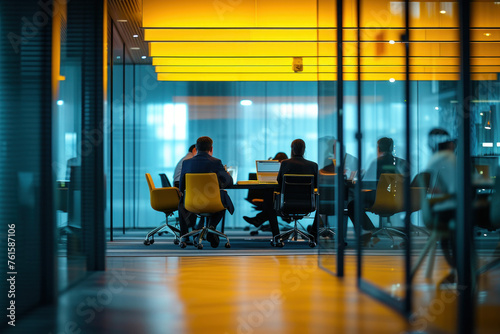 Conference Room Meeting with People Sitting at Table Under Yellow Lights and Glass Walls