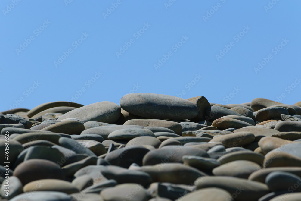 Gray stones on the seashore against the blue sky