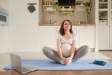 Pregnant woman doing yoga in the home kitchen in the butterfly pose, exercises to prepare for childbirth