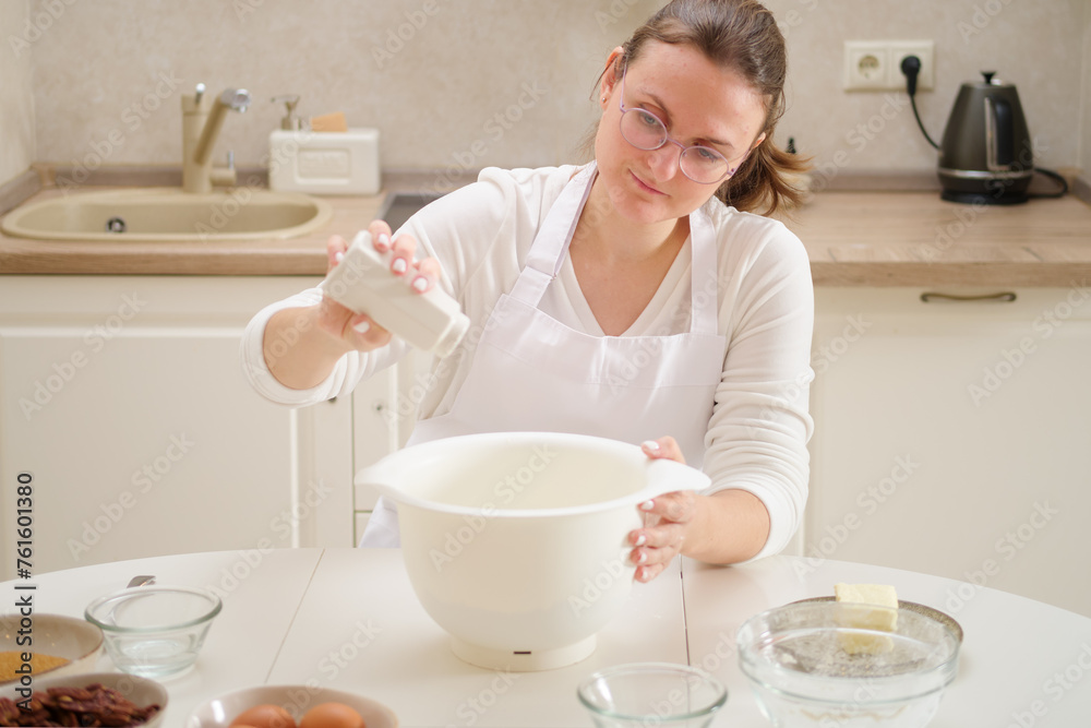 A woman is salting dough from a salt shaker. Process of cooking pecan pie in home kitchen for American Thanksgiving Day. A woman is salting dough from a salt shaker. Process of cooking pecan pie in home kitchen for American Thanksgiving Day.