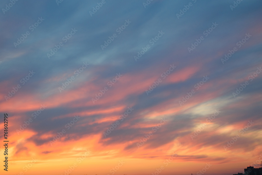 Stunningly beautiful multi-colored violet-pink-lilac evening sky with the yellow light of the setting sun, multi-colored clouds spreading from the lower horizon