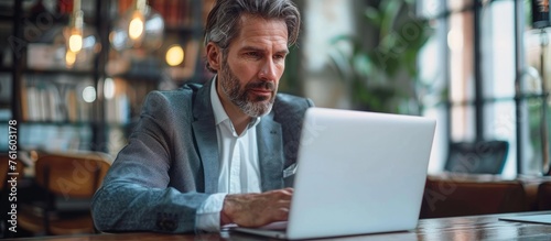 Middle-Aged Businessman Focused on Digital Marketing through Laptop in Professional Environment