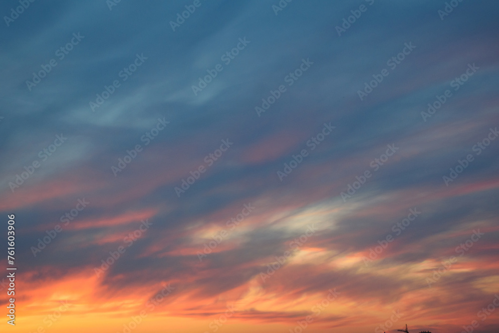 Stunningly beautiful multi-colored violet-pink-lilac evening sky with the yellow light of the setting sun, multi-colored clouds spreading from the lower horizon