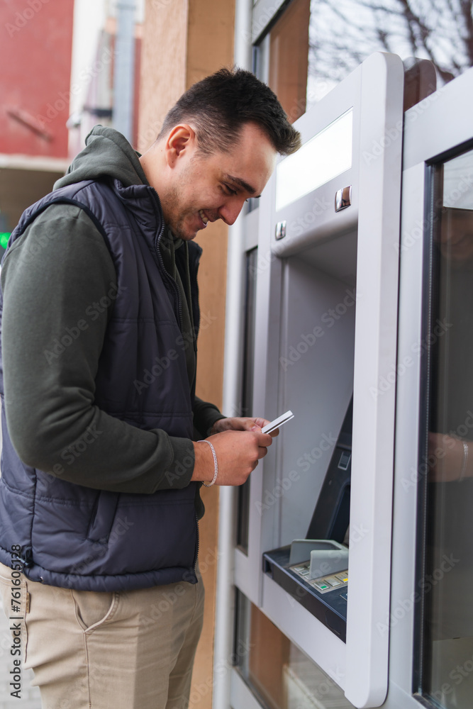 A one young man withdrawing money on ATM with credit card in the city A one young man withdrawing money on ATM with credit card in the city
