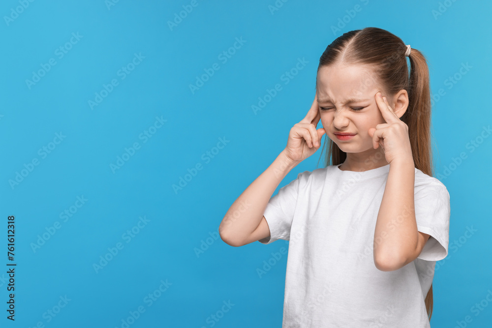 Little girl suffering from headache on light blue background. Space for text Little girl suffering from headache on light blue background. Space for text