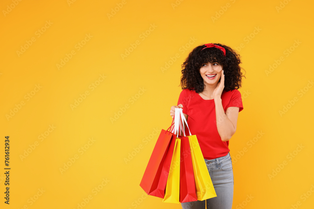 Happy young woman with shopping bags on yellow background Happy young woman with shopping bags on yellow background