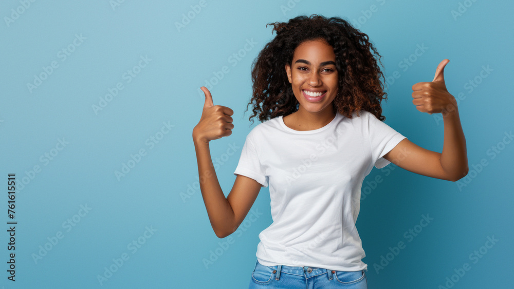 A smiling black woman in a white t-shirt expressing positivity with a thumbs up gesture on a blue background A smiling black woman in a white t-shirt expressing positivity with a thumbs up gesture on a blue background