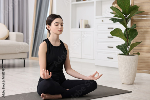 Beautiful girl meditating on yoga mat at home