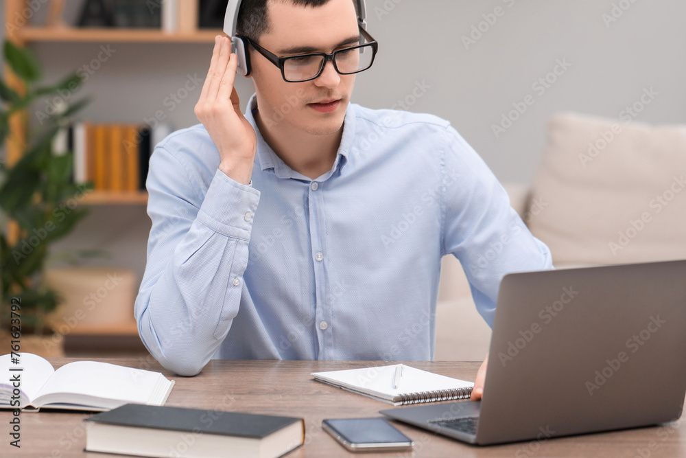 Fototapeta premium E-learning. Young man using laptop during online lesson at table indoors.