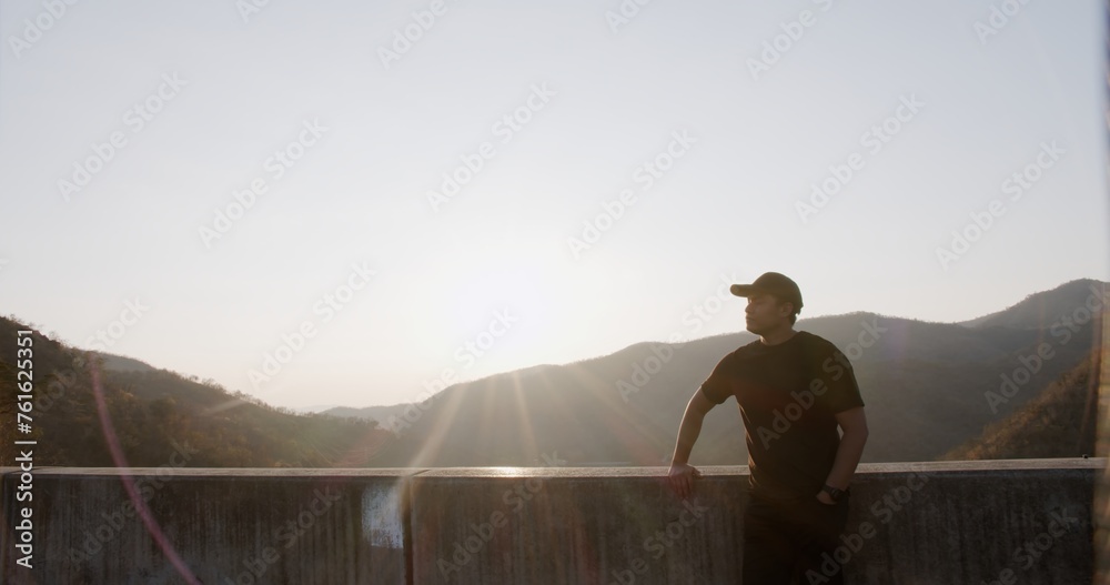 Obraz premium A man stands on a ledge looking out over a mountain range